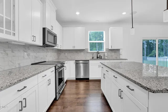 a kitchen with granite countertop white cabinets and white stainless steel appliances