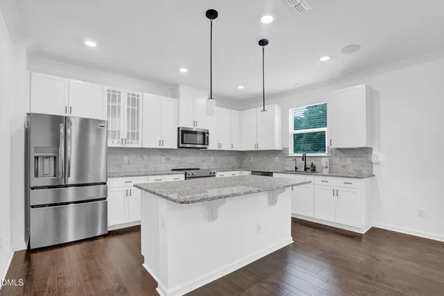 a kitchen with stainless steel appliances granite countertop a sink a stove a refrigerator and island with wooden floor