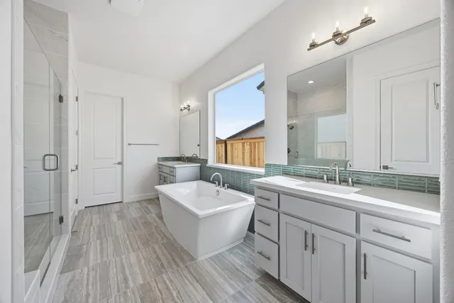 a spacious bathroom with a double vanity sink a mirror and a bathtub