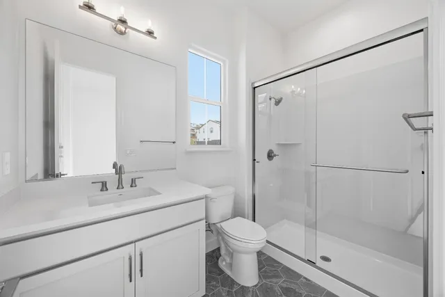 a bathroom with a shower sink vanity mirror and toilet