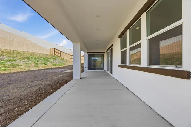 a view of an empty room with wooden floor and windows