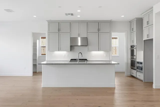 a large kitchen with stainless steel appliances granite countertop a stove a sink and a refrigerator