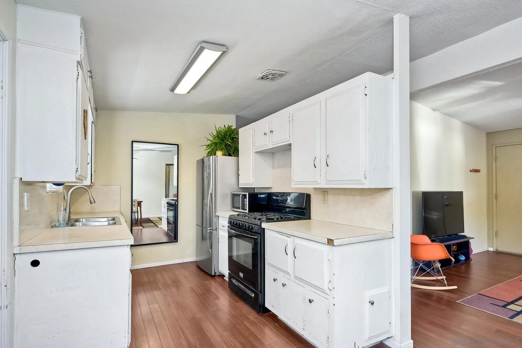 9267 Fairlawn Street Santee, CA 92071 - Photo 13 of 25 a kitchen with stainless steel appliances a stove top oven a sink a refrigerator white cabinets and wooden floor