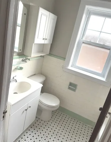 a bathroom with a sink a toilet a window and vanity