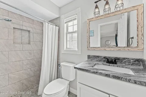a bathroom with a granite countertop toilet sink and mirror