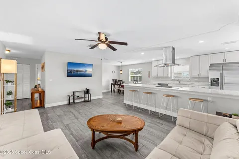 a living room with stainless steel appliances kitchen island granite countertop furniture and a rug
