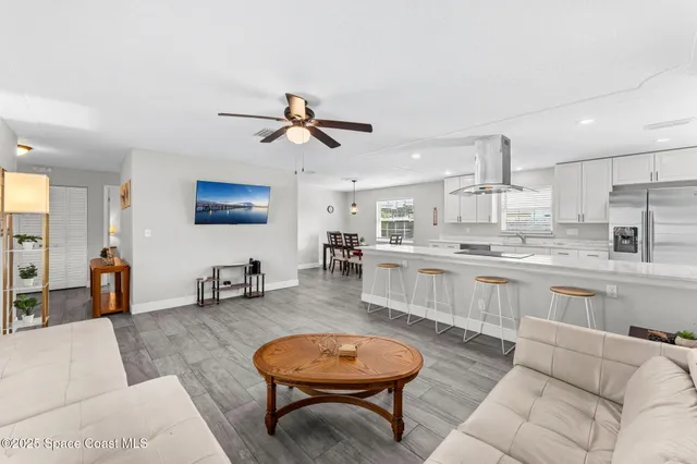 a living room with stainless steel appliances kitchen island granite countertop furniture and a rug