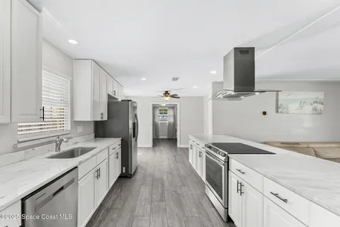 a large kitchen with a large counter top sink and stainless steel appliances