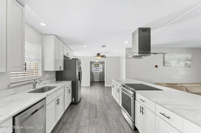 a large kitchen with a large counter top sink and stainless steel appliances
