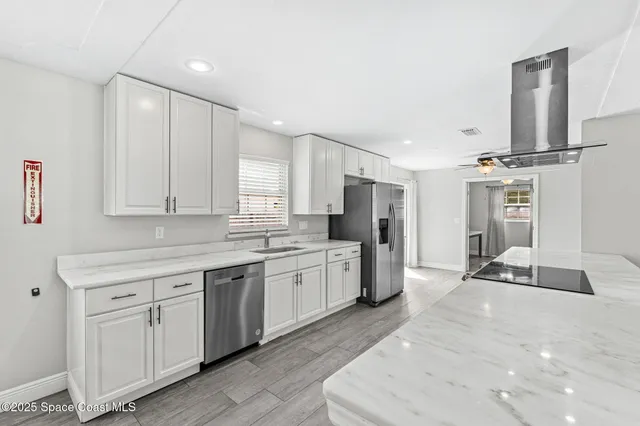 a large white kitchen with cabinets appliances and a sink