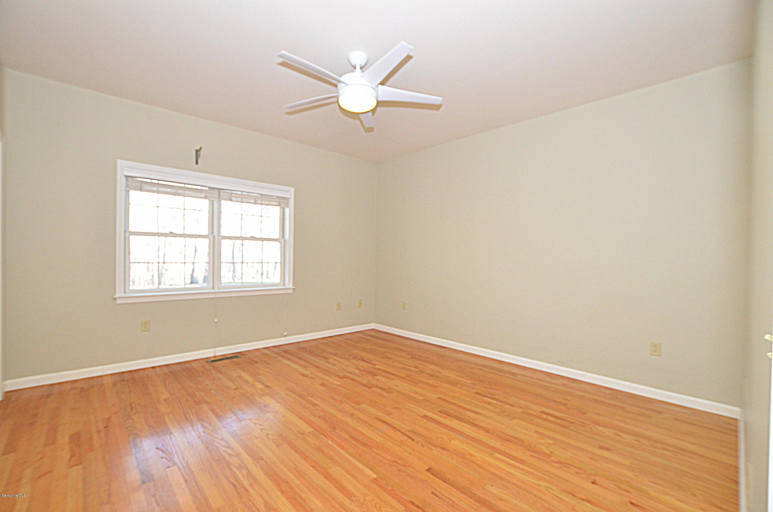 2307 Jacobs Ladder Road Becket, MA 01223 - Photo 21 of 55 an empty room with wooden floor fan and windows