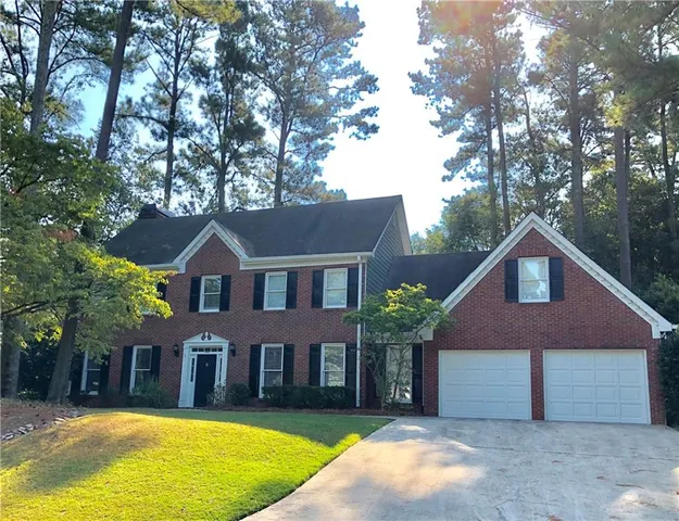 a front view of a house with a yard and large trees
