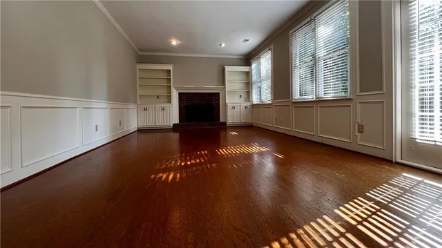 an empty room with wooden floor fireplace and windows