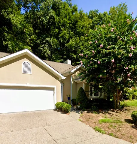 a view of a small space in front of a house with large trees
