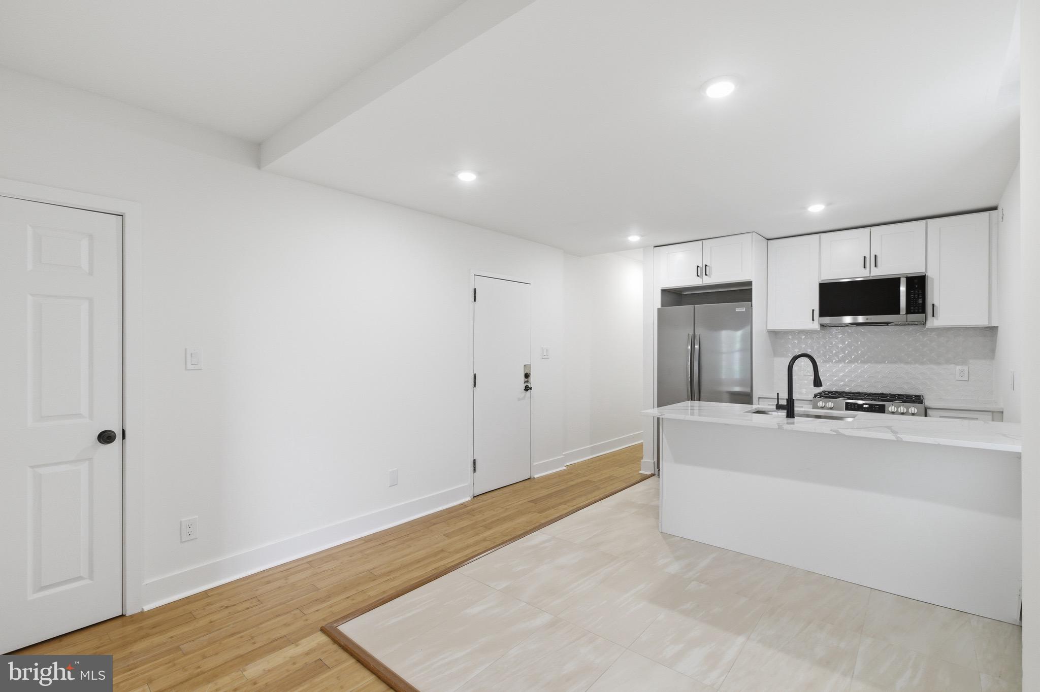 5939 Drexel Road, Unit CARRIAGE Philadelphia, PA 19131 - Photo 7 of 20 a large white kitchen with wooden floor