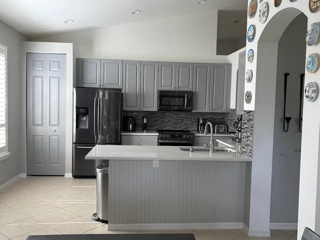 a kitchen with stainless steel appliances granite countertop a refrigerator a stove a sink and a microwave