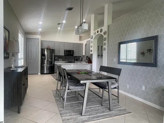 a kitchen with stainless steel appliances kitchen island granite countertop a table chairs sink and cabinets