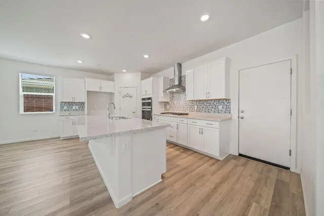 a kitchen with stainless steel appliances white cabinets large wooden floor and a window