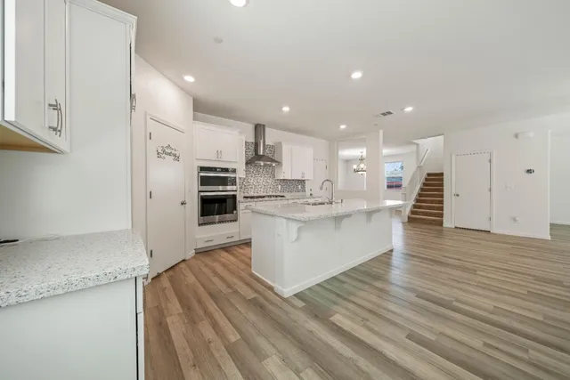 a large kitchen with kitchen island a stove a sink dishwasher and a refrigerator with wooden floor