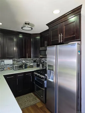 a kitchen with stainless steel appliances kitchen island granite countertop a refrigerator and a stove top oven