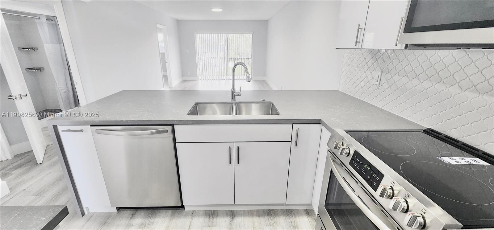 8040 North Colony Circle, Unit 309 Tamarac, FL 33321 - Photo 2 of 15 a kitchen with white cabinets and white appliances