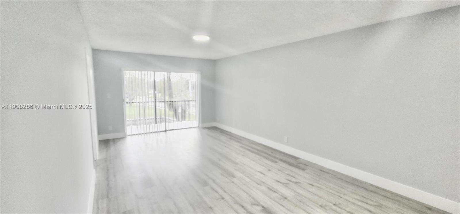8040 North Colony Circle, Unit 309 Tamarac, FL 33321 - Photo 7 of 15 a view of an empty room with wooden floor and a window