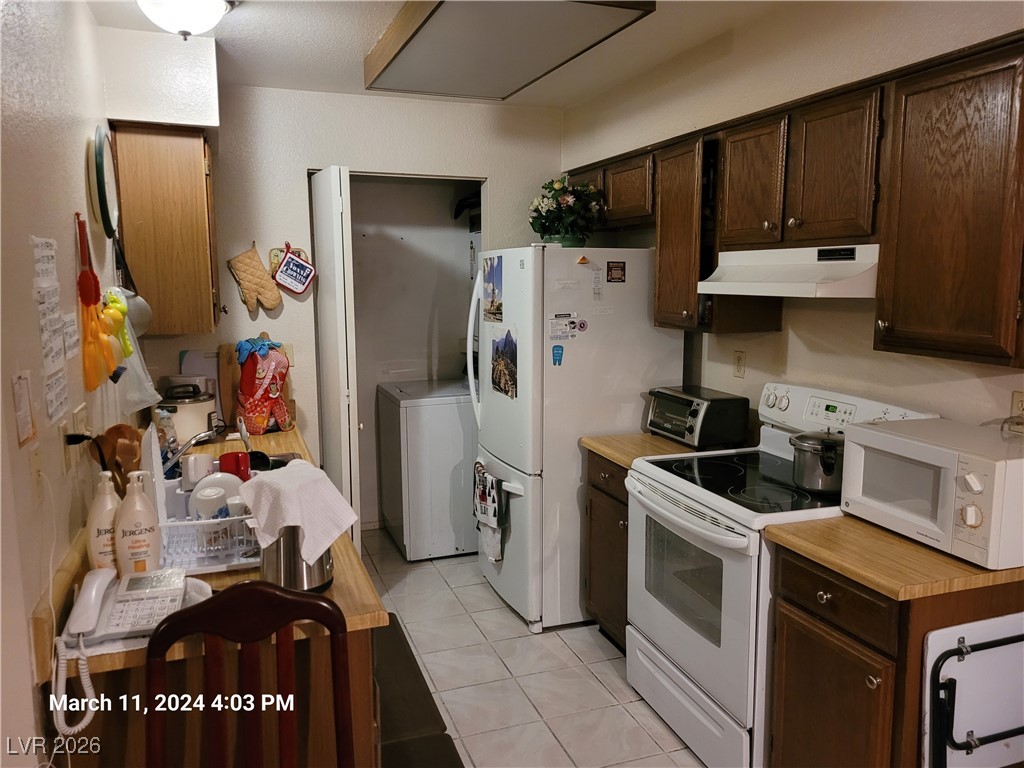 809 Hedge Way, Unit 3 Las Vegas, NV 89110 - Photo 5 of 10 Kitchen with white appliances, dark brown cabinetry, light countertops, and light tile patterned floors