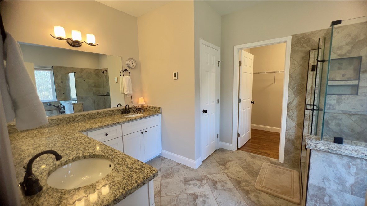 160 Hudgins Lake Road Townville, SC 29689 - Photo 18 of 41 Marble-look tile flooring complements the dual granite-topped vanities in this functional primary bathroom.