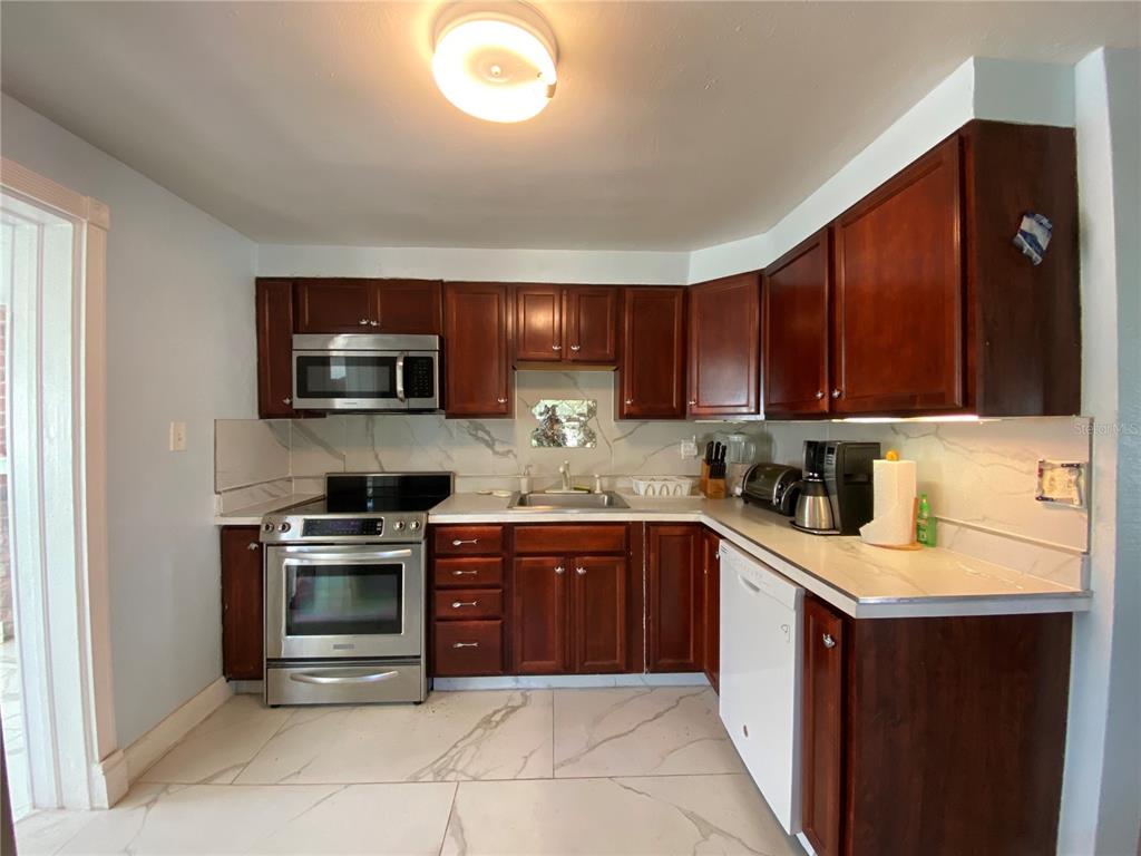 910 Lake Avenue Edgewater, FL 32132 - Photo 11 of 23 a kitchen with stainless steel appliances granite countertop a stove top oven a sink dishwasher and a refrigerator with wooden cabinets