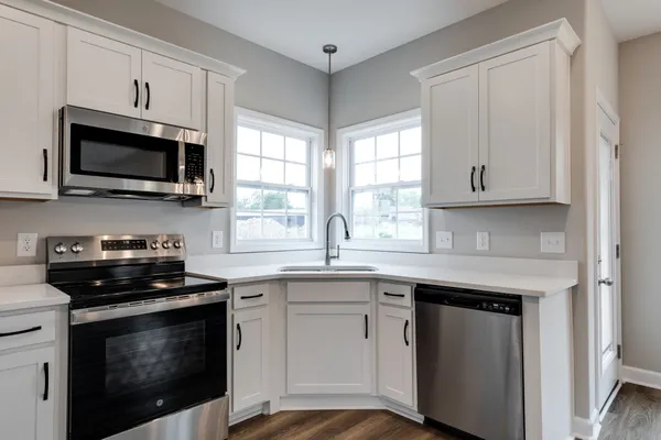 a kitchen with cabinets stainless steel appliances a sink and a window