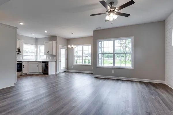 a view of an empty room with window and wooden floor
