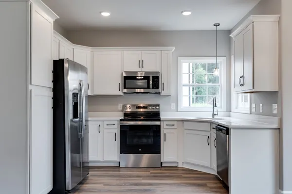 a kitchen with granite countertop a refrigerator stove top oven and sink