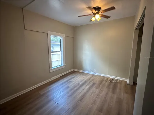 a view of room with window ceiling fan and hardwood floor