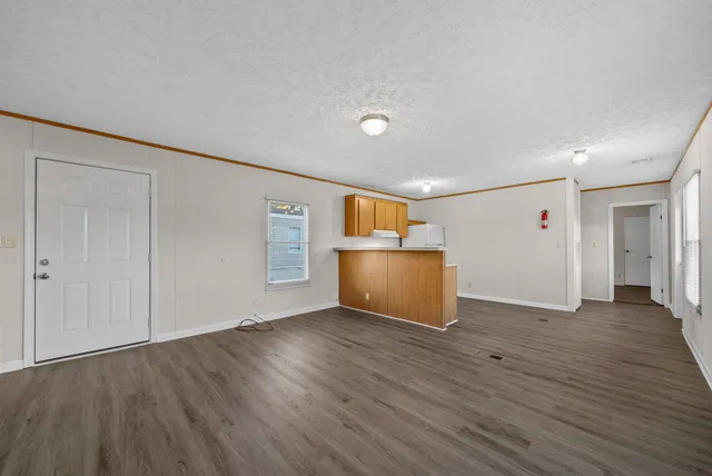 a view of an empty room with wooden floor and closet