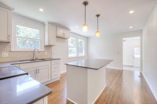 a kitchen with a sink a window and wooden floor