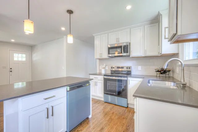 a kitchen with kitchen island granite countertop a sink stainless steel appliances and white cabinets