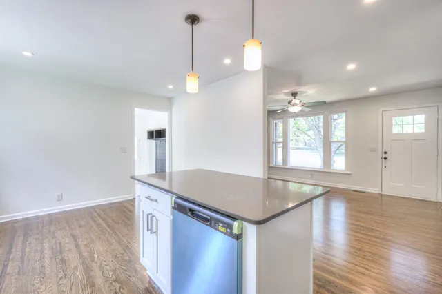 a kitchen with stainless steel appliances granite countertop a sink a window and wooden floor