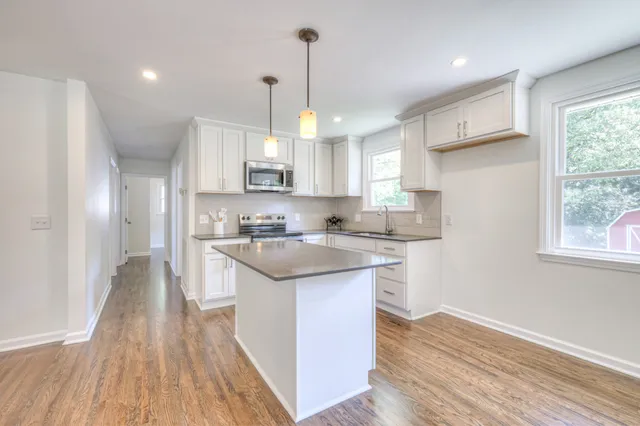 a kitchen with kitchen island granite countertop a sink a counter space appliances and cabinets