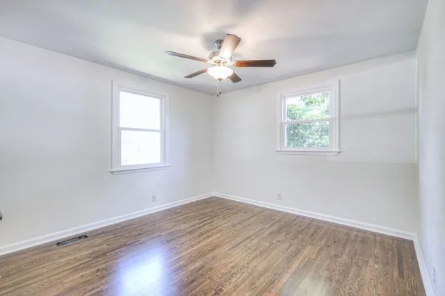 an empty room with wooden floor and ceiling fan