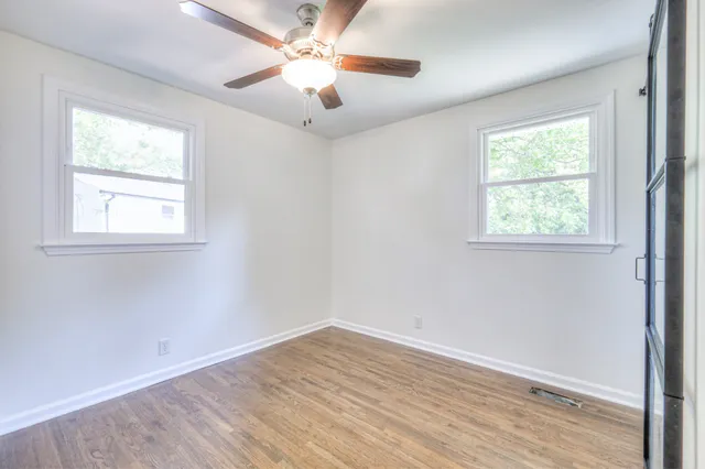 an empty room with wooden floor cabinet and windows
