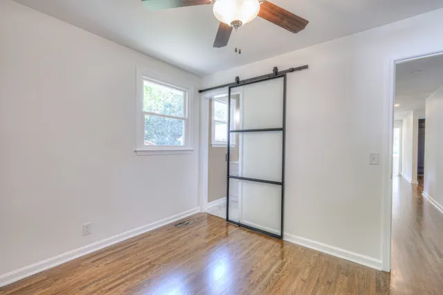 an empty room with wooden floor cabinet and a refrigerator