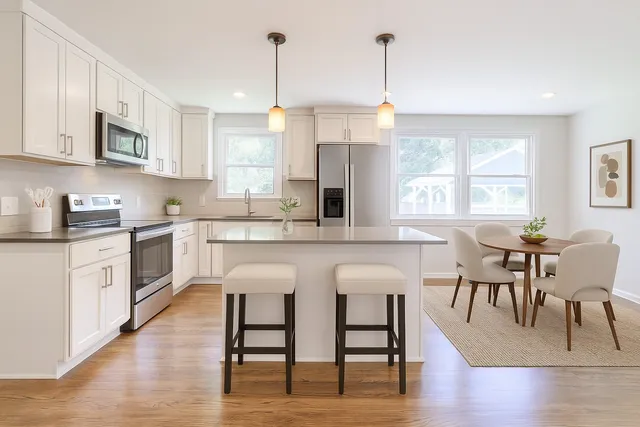 a kitchen with stainless steel appliances granite countertop a stove top oven a sink dishwasher a dining table and chairs with wooden floor