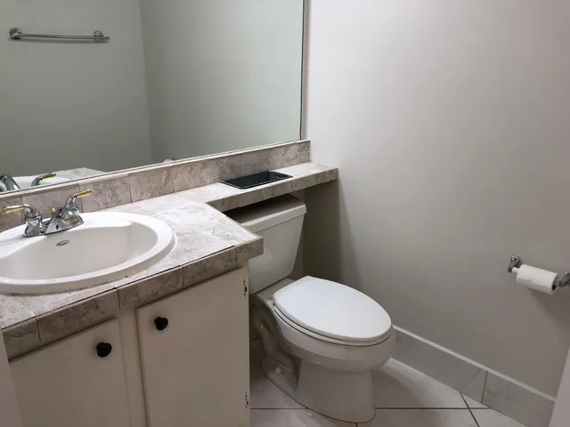 a bathroom with a granite countertop toilet sink and mirror