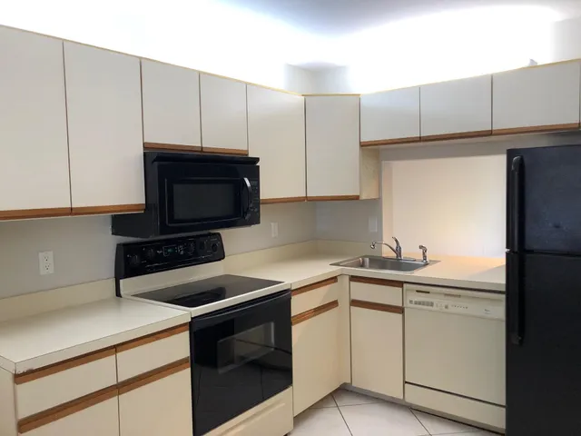 a kitchen with a sink and a stove top oven with white cabinets