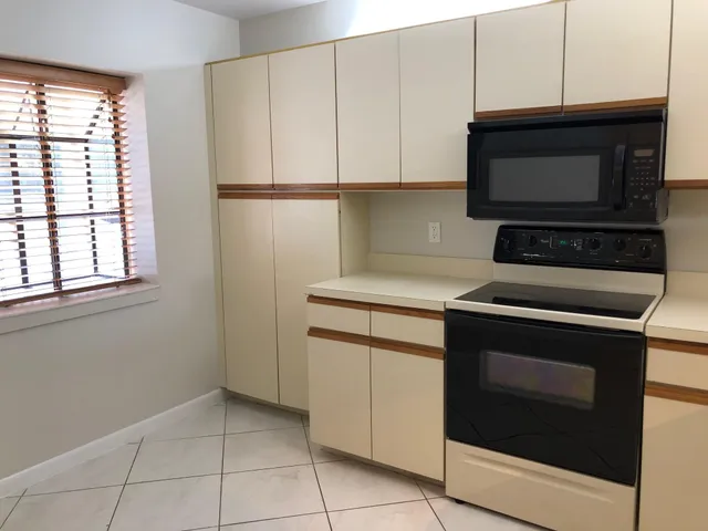 a kitchen with granite countertop white cabinets appliances and a counter space