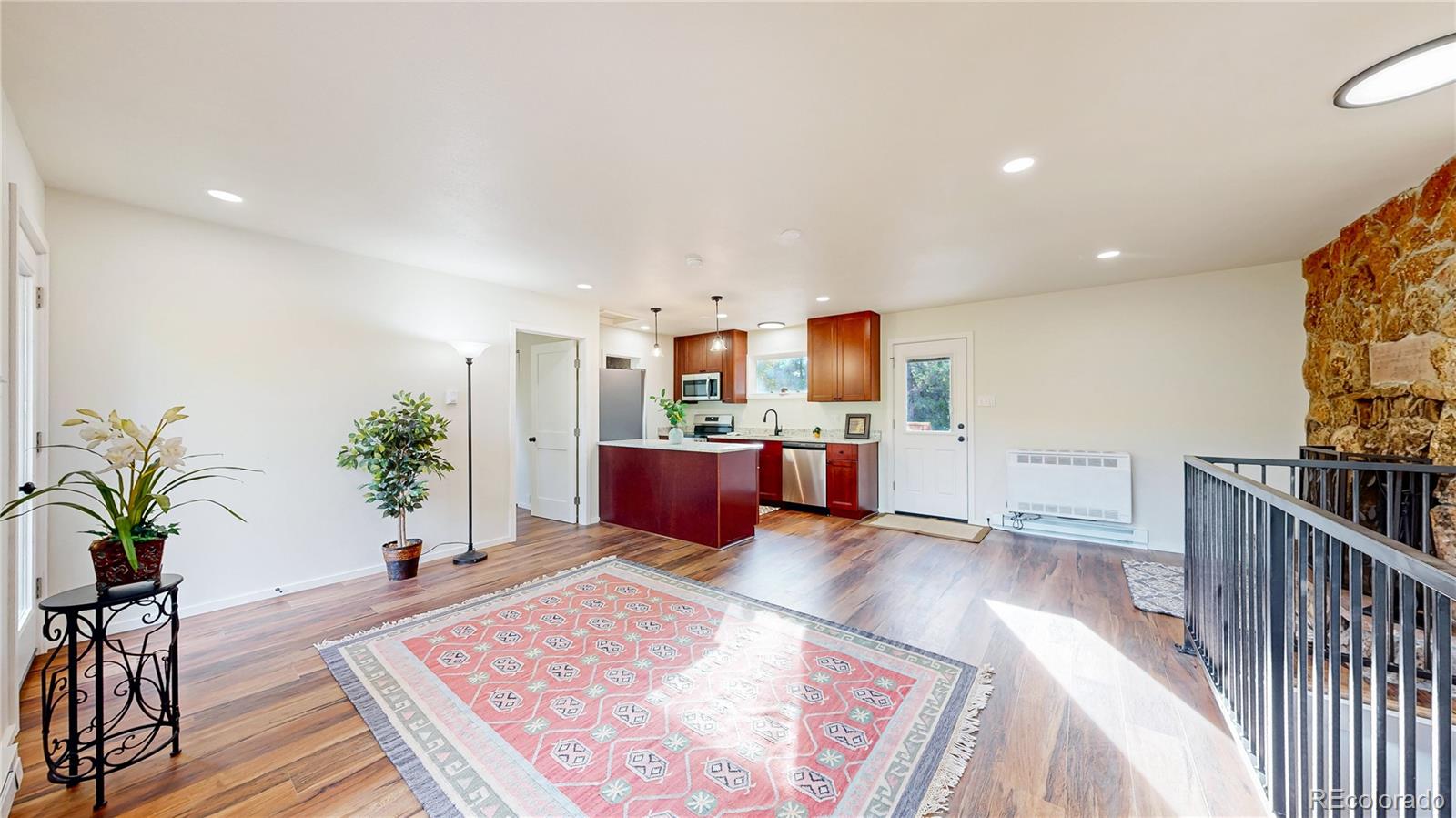 a living room with furniture and potted plants with wooden floor
