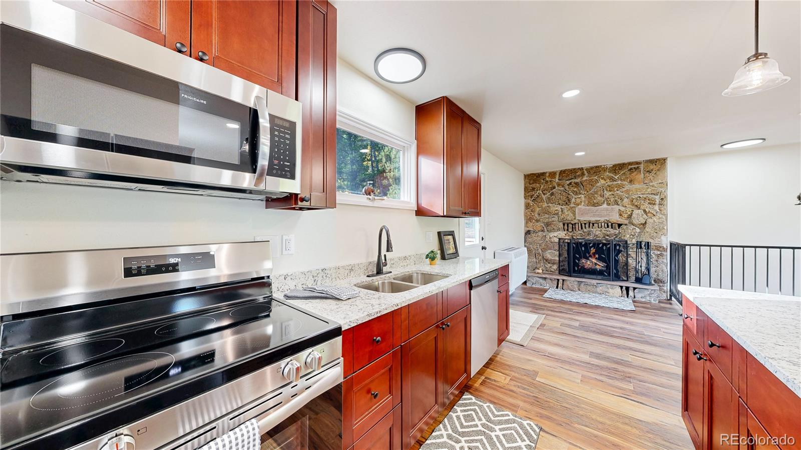 225 Renaud Road Bailey, CO 80421 - Photo 8 of 39 a kitchen with stainless steel appliances kitchen island granite countertop a stove a sink and a microwave