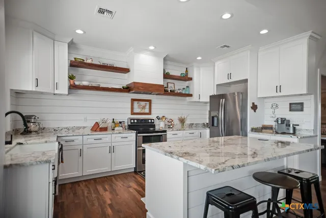 a kitchen with stainless steel appliances granite countertop a refrigerator a stove and a sink with wooden floor