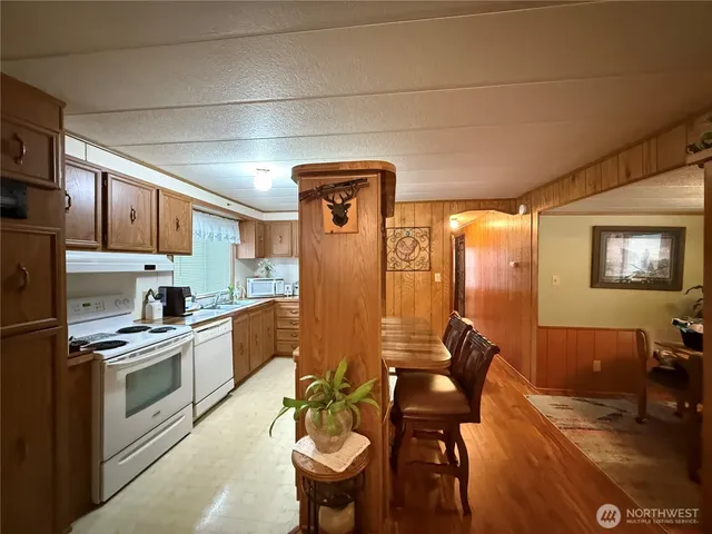 a kitchen with stainless steel appliances granite countertop a stove a sink a refrigerator dining table and chairs with wooden floor