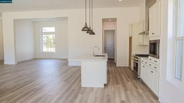 a kitchen with stainless steel appliances a white stove top oven a refrigerator a sink and dishwasher with wooden floor